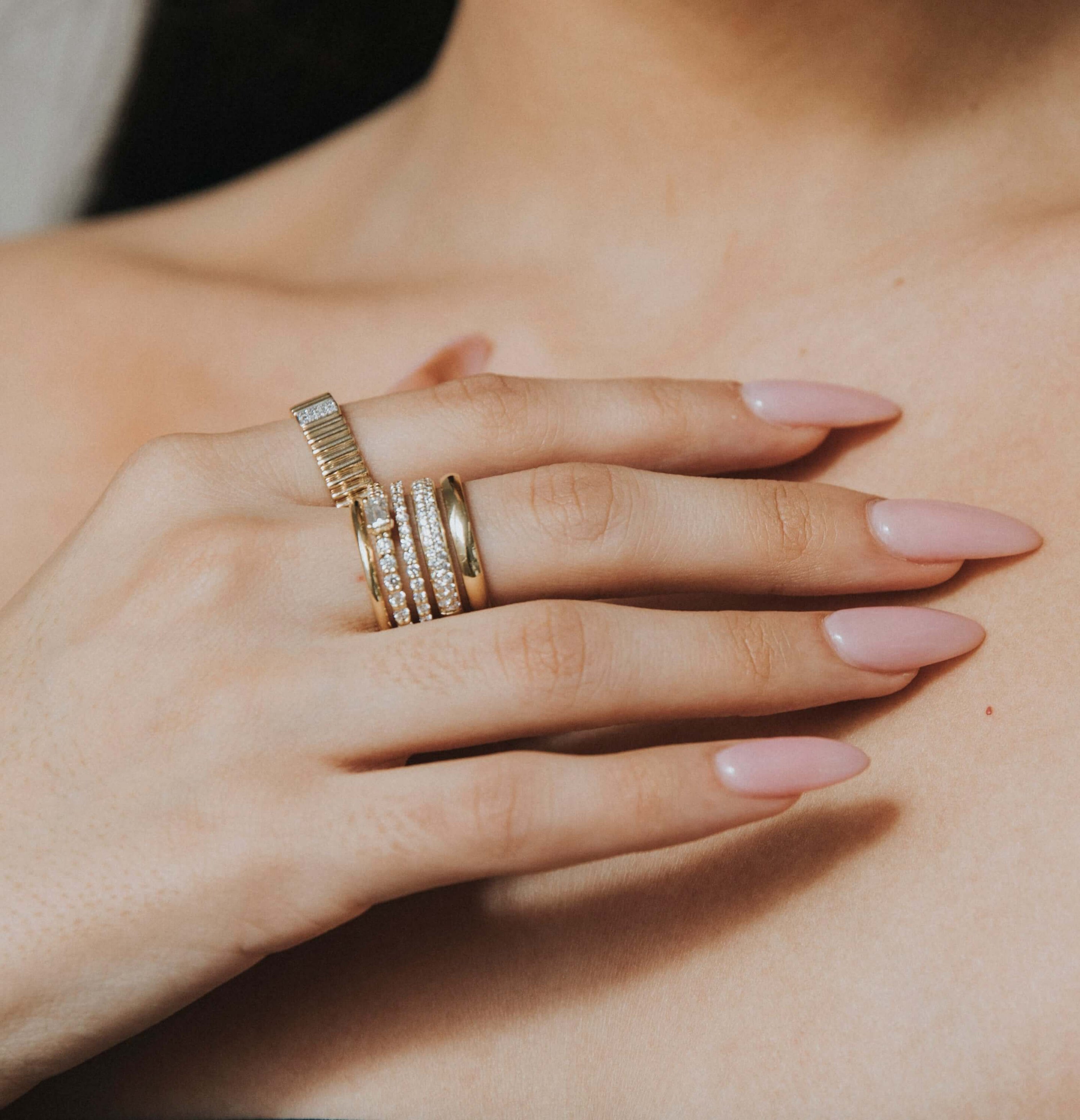 The Multi Band Diamond Ring from Janet Heller Fine Jewelry is crafted in 18KT gold.  The ring features stacked gold bands with small diamonds and a central emerald-cut diamond.