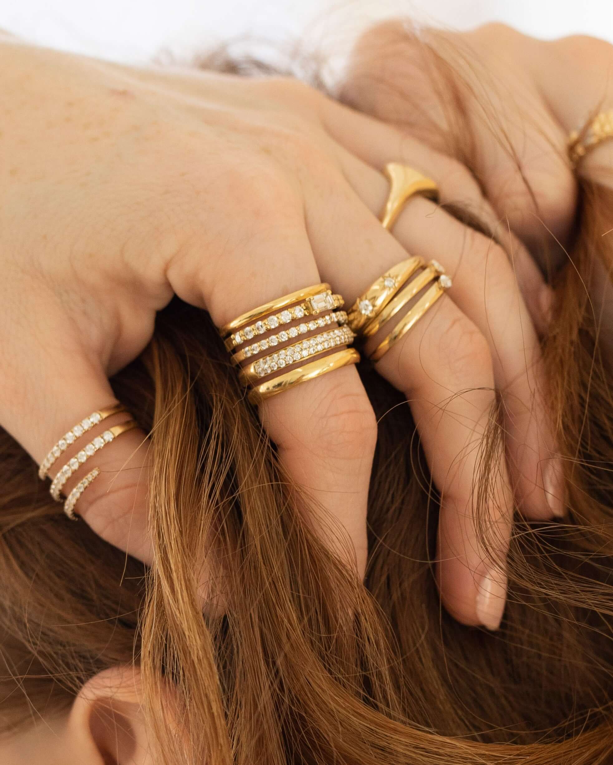 The Multi Band Diamond Ring from Janet Heller Fine Jewelry is crafted in 18KT gold.  The ring features a baguette center stone with multiple bands some plain while others are adorned with round diamonds.