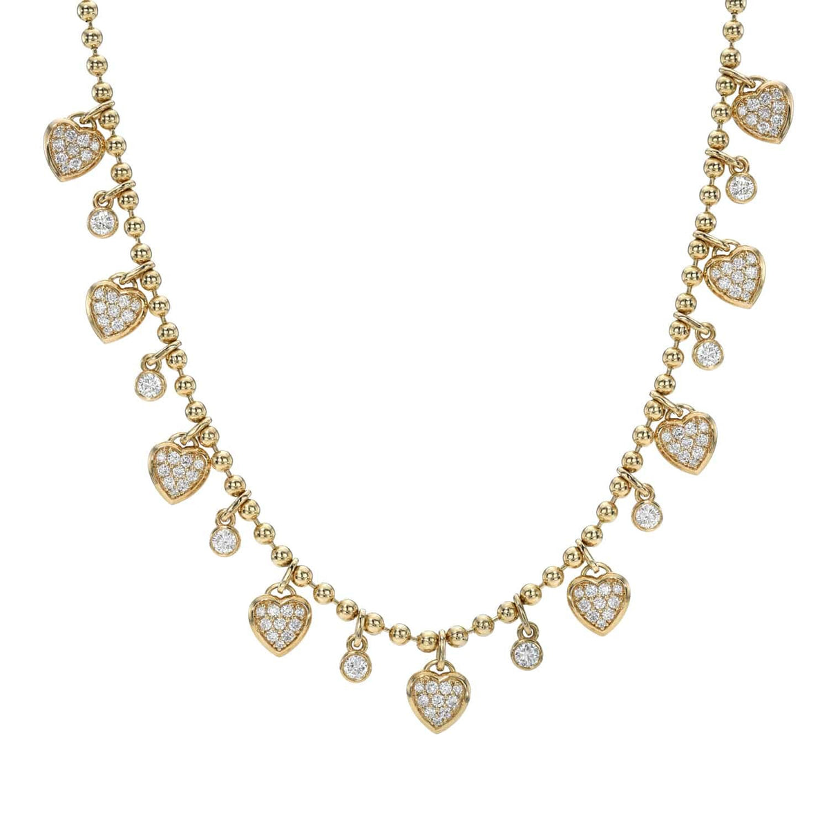 The Diamond Dangle Heart Necklace by Janet Heller is a stunning piece of fine jewelry, featuring small round gold beads and alternating heart-shaped and round diamond-studded charms hanging along the chain, beautifully displayed on a white background.