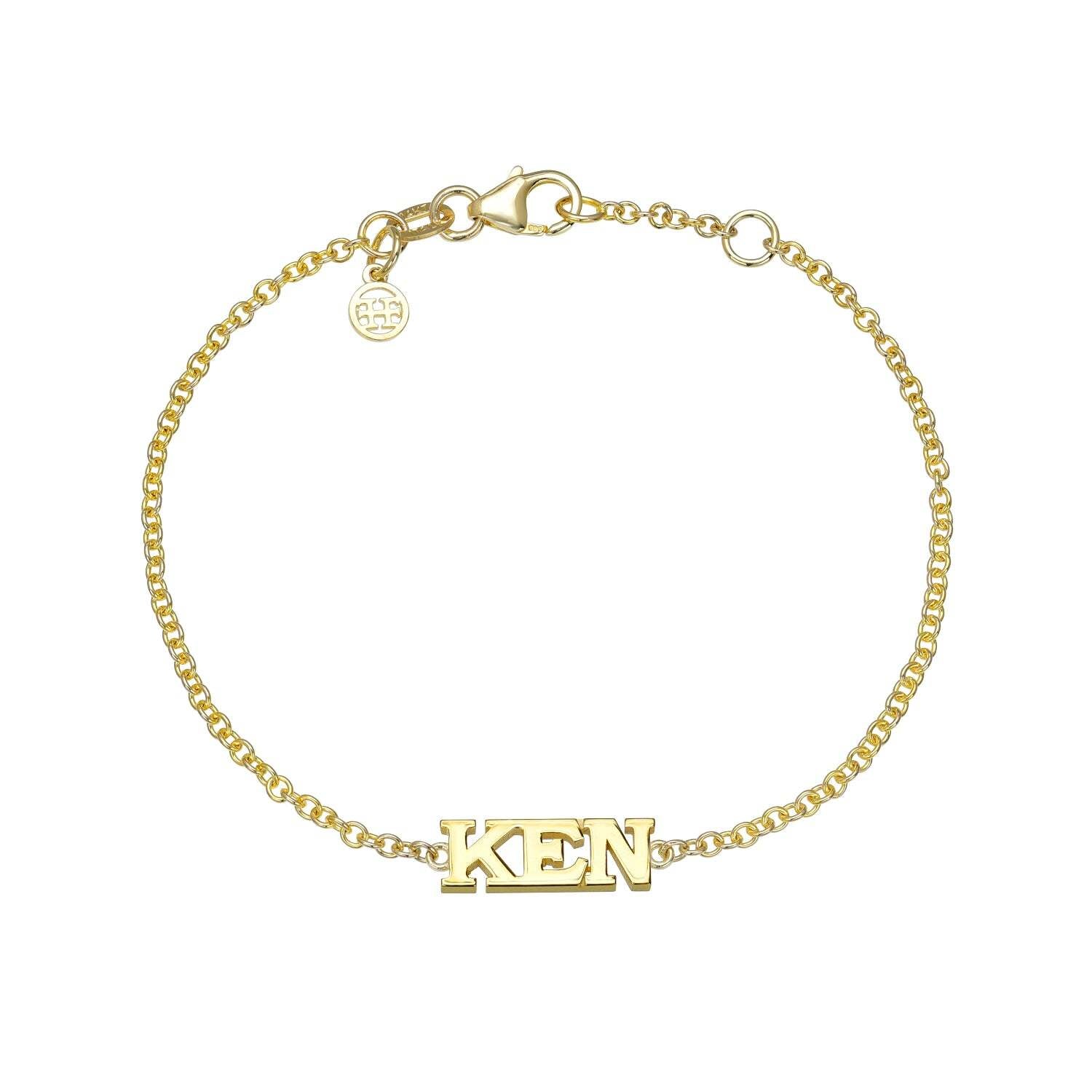 Block Name Bracelet with a gold chain, lobster clasp, and a small circular charm. The centerpiece showcases the word KEN in bold, uppercase letters—an elegant piece of personalized jewelry that adds a distinctive touch to your collection.