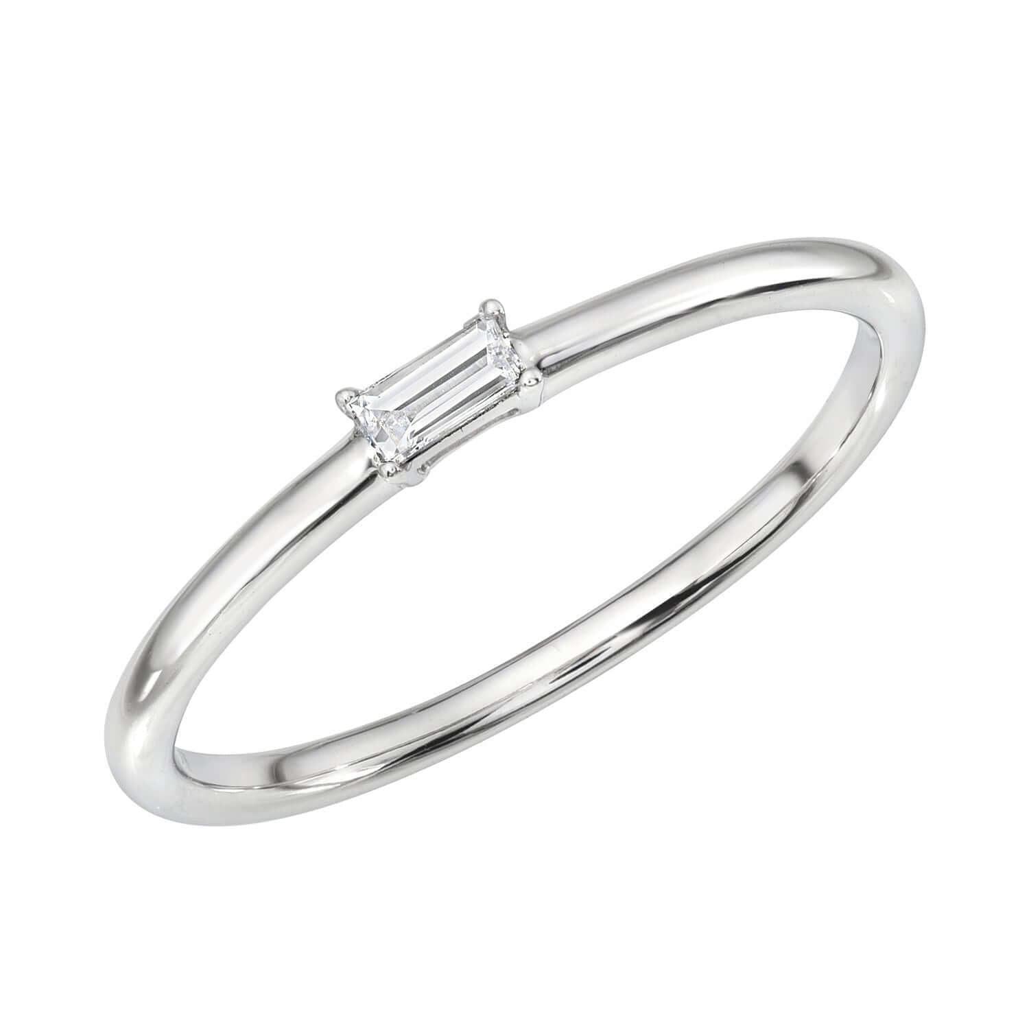 The Single Baguette Diamond Stacking Ring from Janet Heller’s fine jewelry collection features a thin silver band with a small, horizontally set rectangular baguette-cut diamond at the center, and is available for preorder.