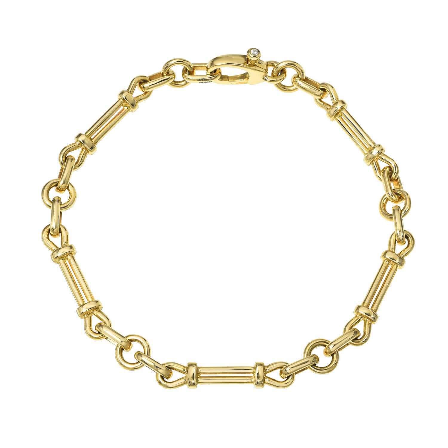 Introducing the Lisbon Bracelet from Janet Heller Fine Jewelry—a gold bracelet featuring alternating cylindrical and round link sections, complemented by a clasp adorned with a small gem. This elegant and classic design exemplifies timeless style. For custom jewelry requests or inquiries, please contact us.