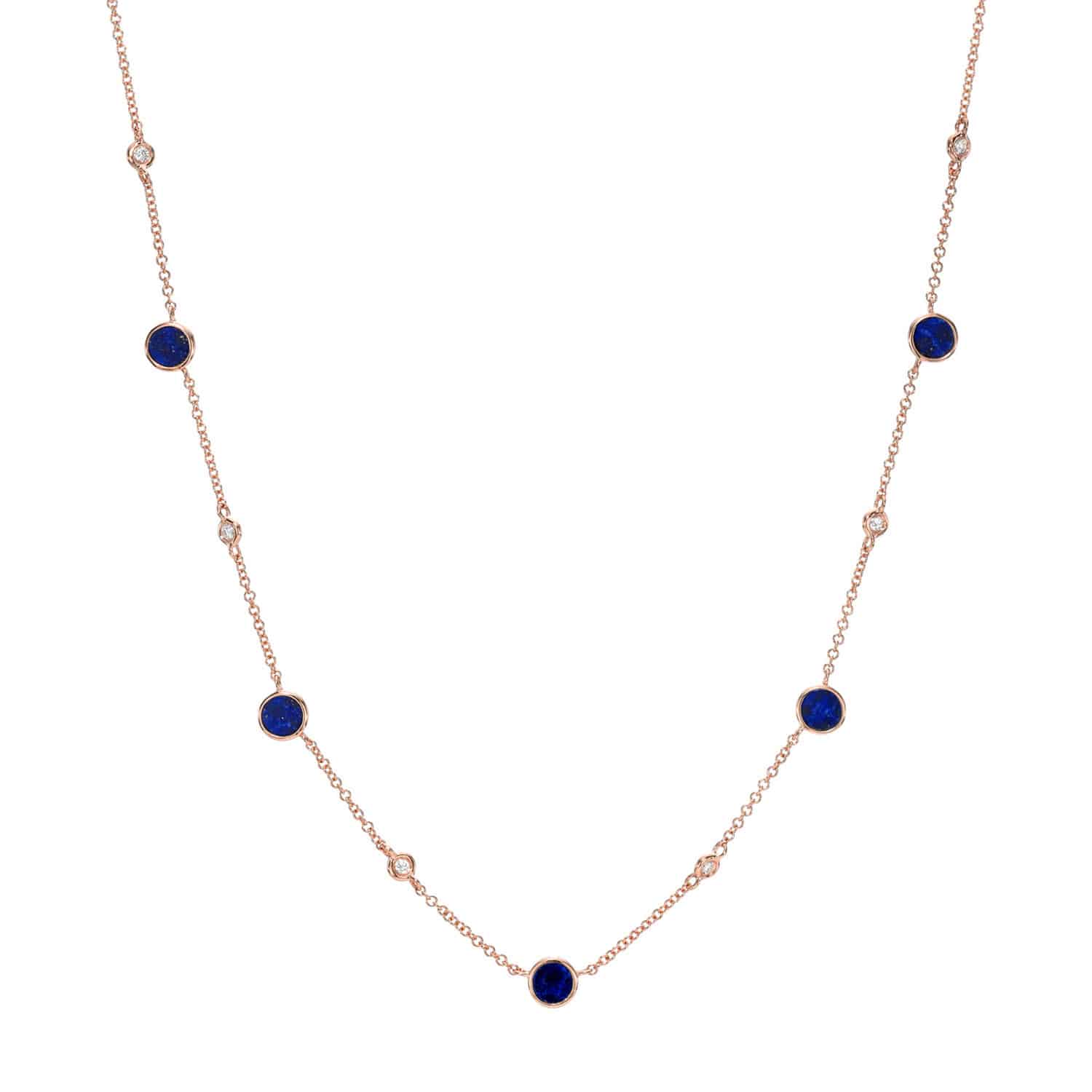 The Lapis Piper Necklace features a delicate gold chain adorned with evenly spaced round blue lapis gemstones and small clear stones set in bezels. Its simple and elegant design showcases alternating lapis and clear accents along the chain.
