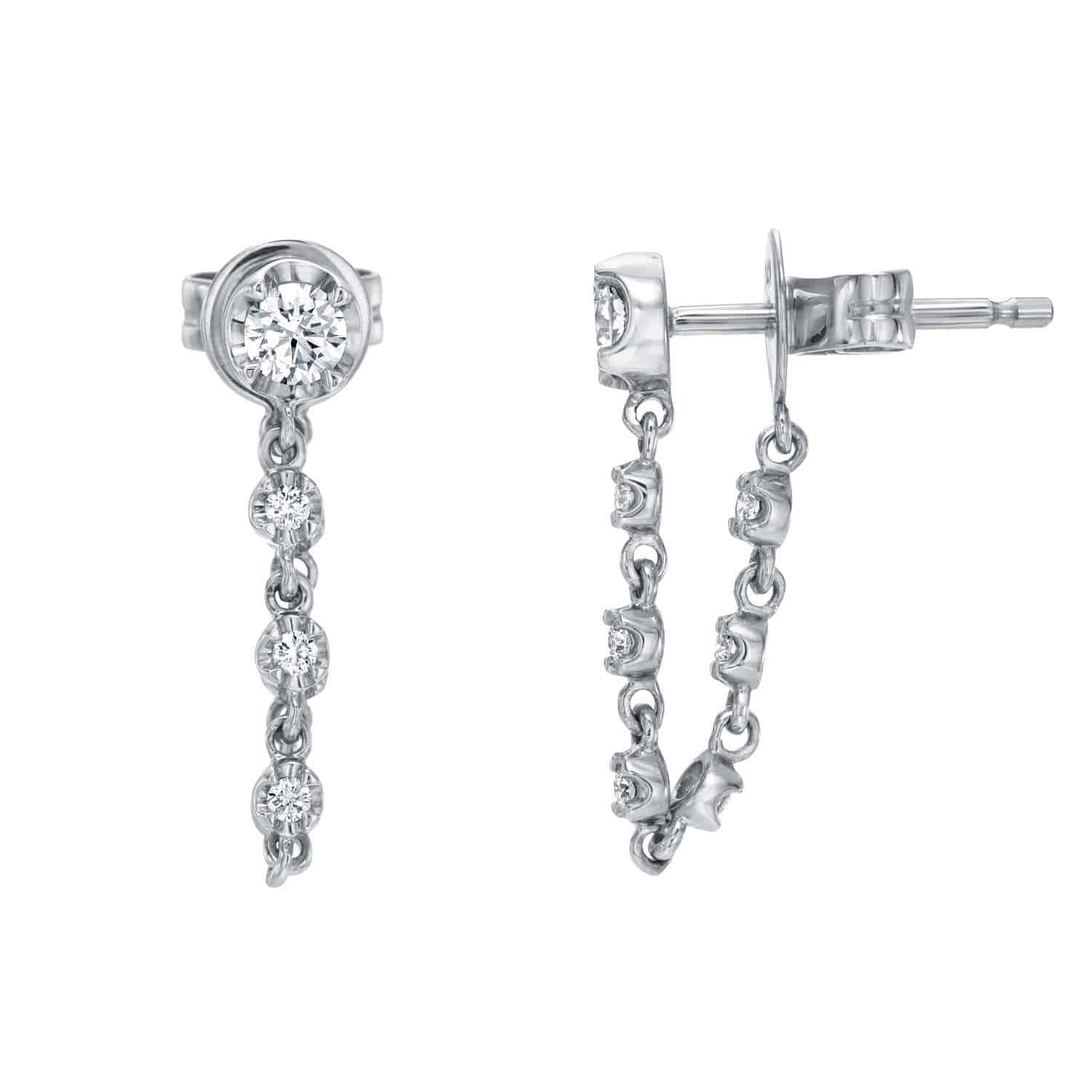 A pair of Diamond Henley Studs featuring a silver drop design with a round stud and three small dangling diamonds, displayed from the front and side on a white background. This elegant piece by Janet Heller Fine Jewelry exemplifies the artistry of custom jewelry, perfect for those seeking timeless sophistication. For jewelry inquiries, please contact us directly.