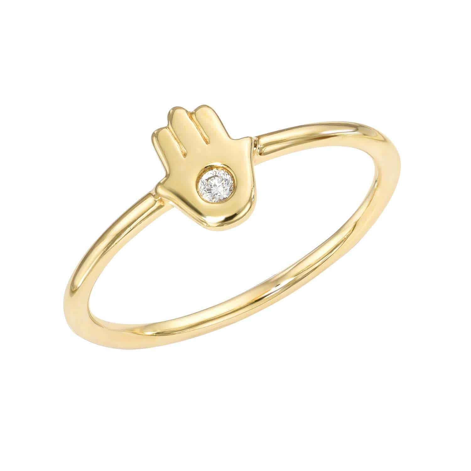 Introducing the Diamond Hamsa Ring: a gold ring with a slender band, showcasing a central Hamsa hand design accented by a delicate round diamond in the heart of the palm. This exquisite fine jewelry piece by Janet Heller is available for preorder—perfect for those who seek timeless elegance.