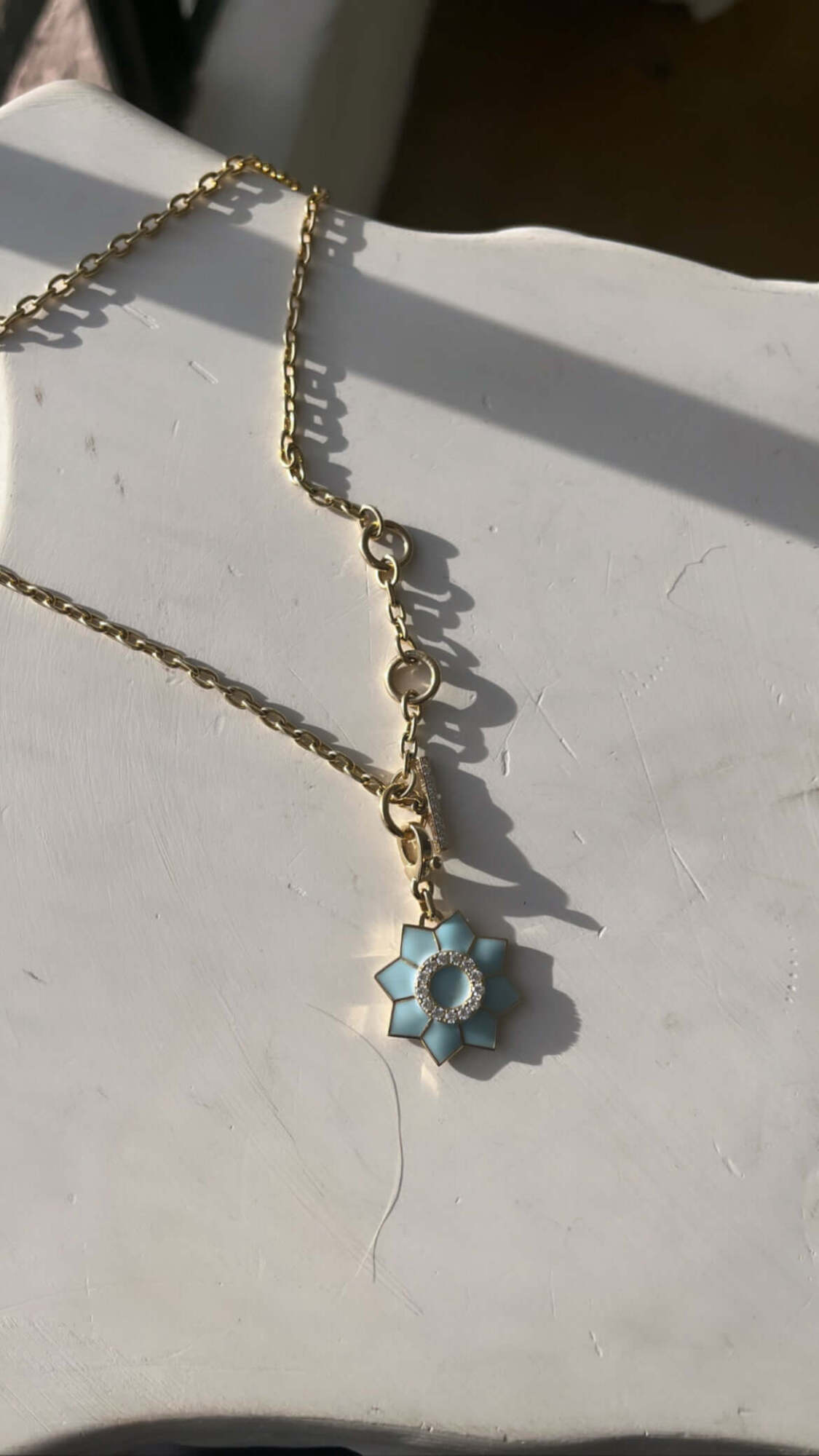 The Enamel & Diamond Flower Charm necklace by Janet Heller Fine Jewelry, features a blue flower pendant with a circular center surrounded by diamonds.  The clasp which adorns a single diamond clips easily onto various Janet Heller Fine Jewelry necklaces and chains.  