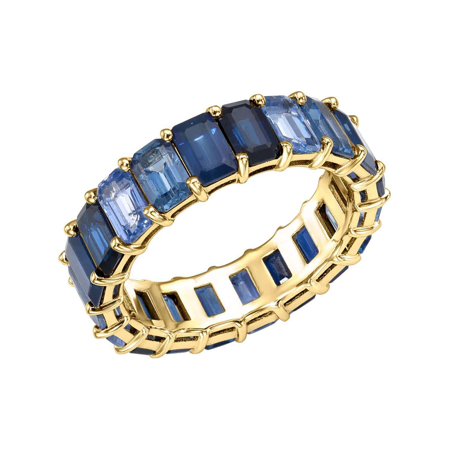 The Blue Sapphire Ombre Ring features a gold band adorned with rectangular blue sapphires in graduated shades, arranged in a continuous row around the band. Available for preorder in multiple sizes and vibrant color combinations.