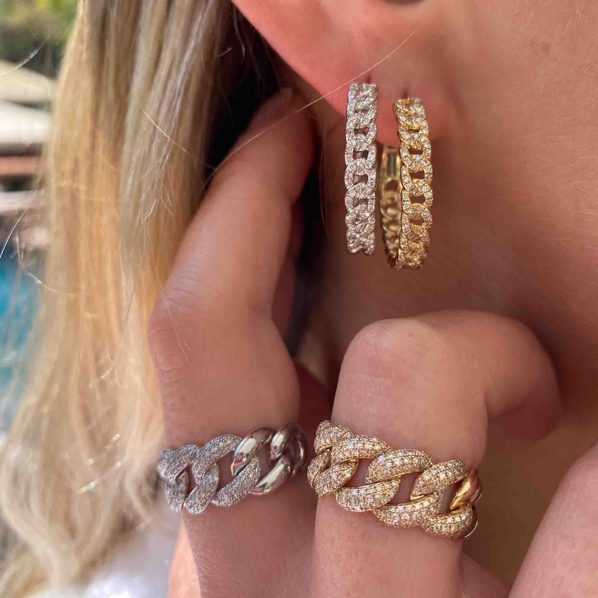 Close-up of a woman wearing the Chain Link Easton Hoops—gold and silver chain-link hoop earrings encrusted with small diamonds—and matching chain-link rings, all a stunning showcase of fine jewelry by Janet Heller.