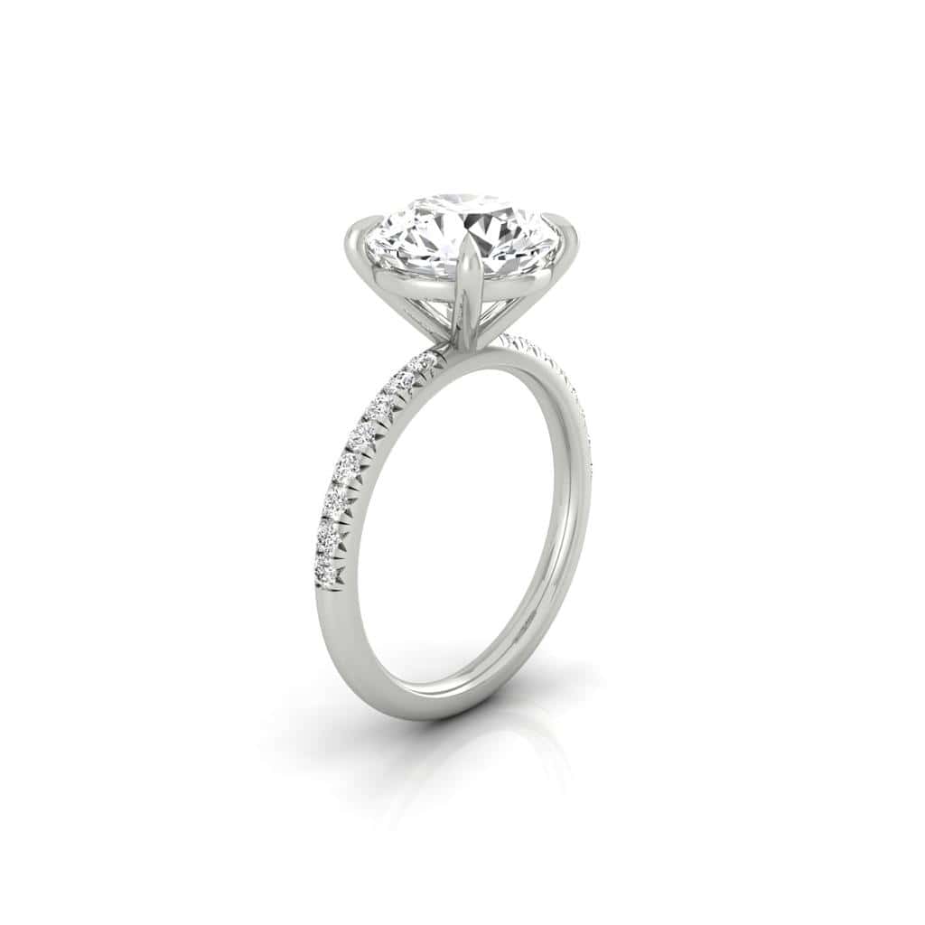 The Amélie is a silver engagement ring with a prong-set round center diamond on a thin band, accented by French Pavé small diamonds for added sparkle and elegance, displayed against a plain white background.