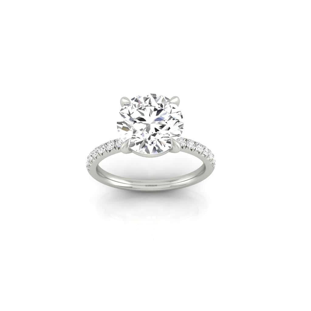 The Amélie engagement ring showcases a large round center diamond solitaire with a stunning French Pavé band. Prong-set smaller diamonds add elegance and sparkle against the plain white backdrop.