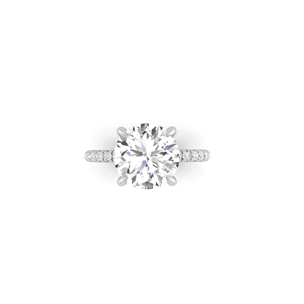 The Amélie ring features a prong-set, round-cut center diamond, beautifully enhanced by a band adorned with smaller diamonds in a French Pavé setting, all showcased on a white background.