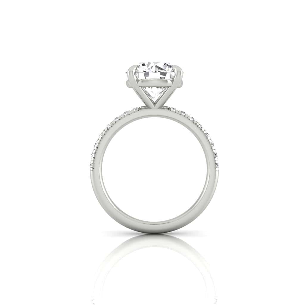 Side view of the Amélie silver engagement ring featuring a prong-set, round-cut center diamond. The band is elegantly enhanced with a French Pavé of small diamonds. Displayed against a white background, this exquisite piece exudes timeless sophistication.